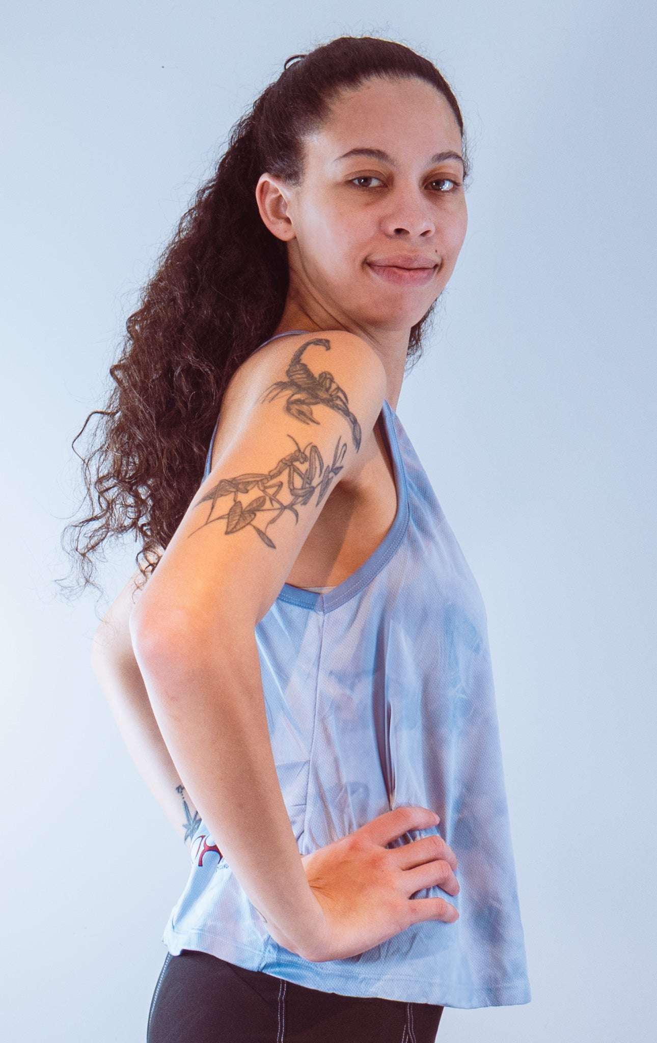 Woman wearing a sleeveless tie dye bike top in blue with strappy back and side pocket for cycling.